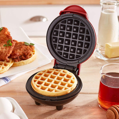 Mini waffle maker with a waffle inside on a kitchen counter.