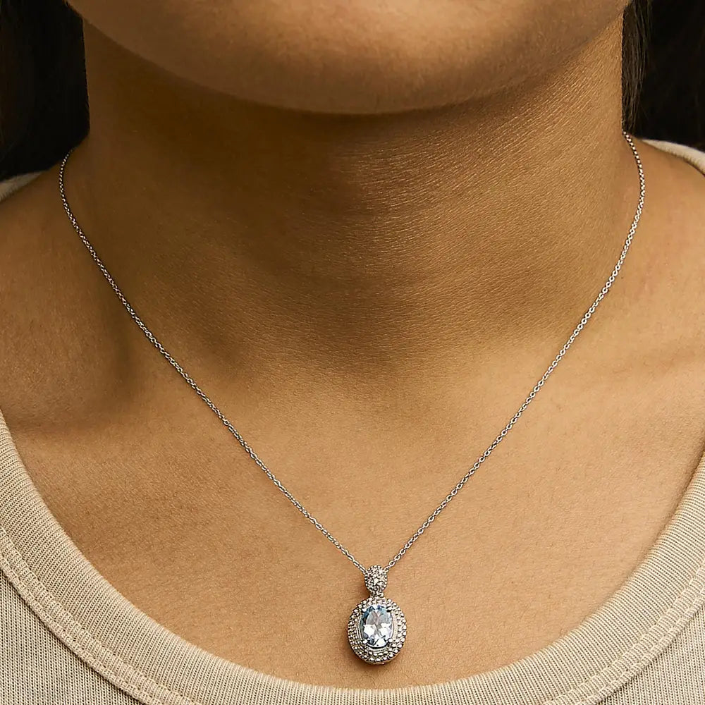 Oval Blue Topaz and Diamond Beaded Halo Pendant in Sterling Silver